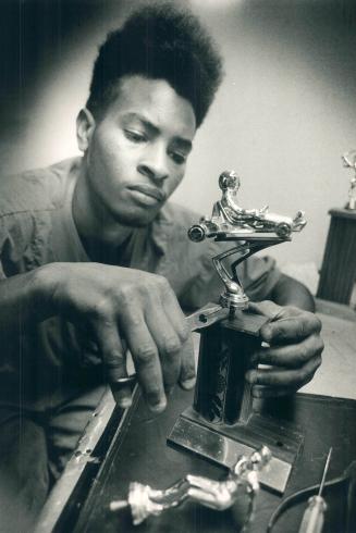 A sure winner, Barry Mitchell assembles a sports trophy for Rite Rubber Stamp of Toronto, which builds engraves signs and makes rubber stamps