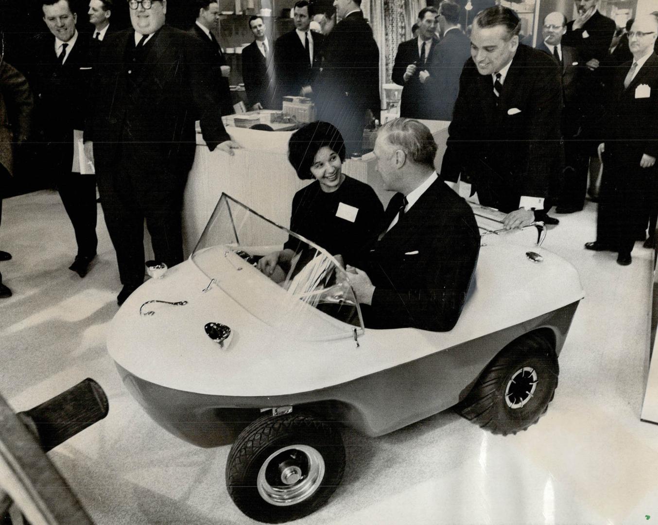 It doesn't jump puddles . . . it rides 'em, Industry Minister C. M. Drury tries out The Penguin, a Canadian-designed, two-seat amphibian car on displa(...)