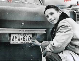 Basil Baker easily puts the 1974 registration on his car by placing a small red sticker (circled) on the 1973 rear license plate. No more knuckle-scr(...)