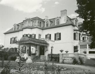 Image shows the front of a three storey house with a garden.