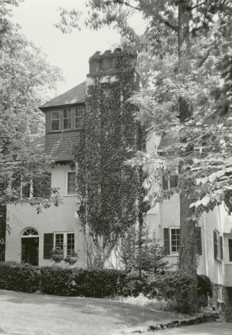 Image shows a very limited view of a three storey residential house with some trees around it.