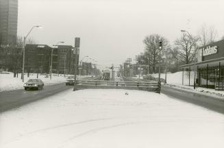 Image shows a street view with some cars and a streetcar on it. There are some multi floor buil…