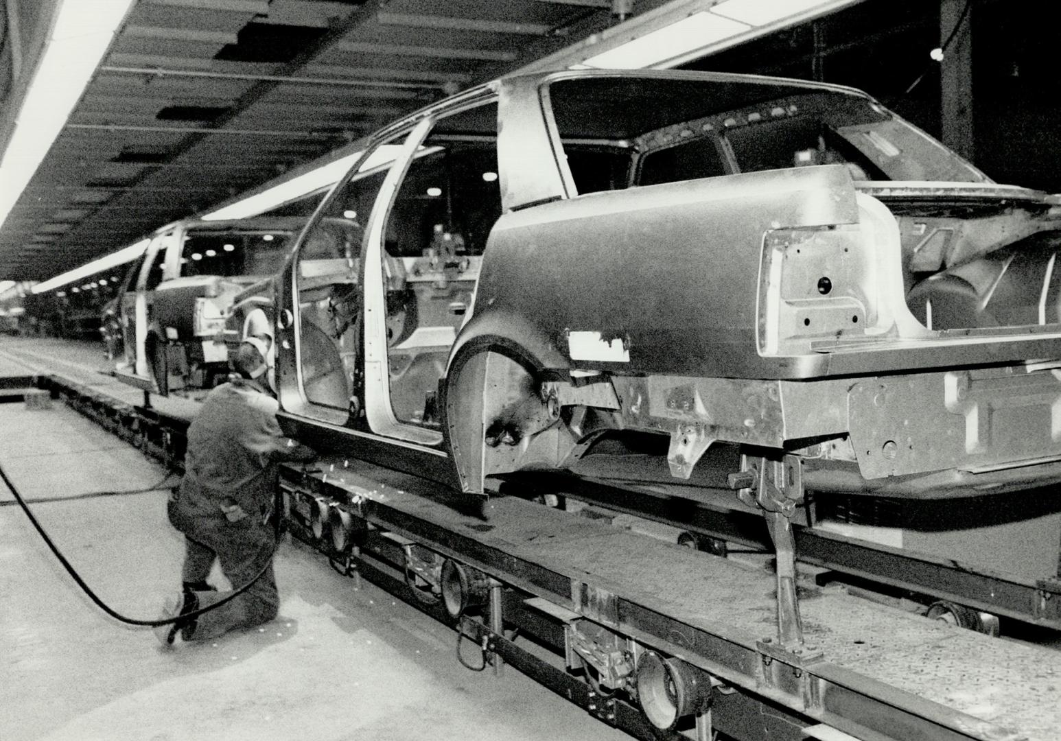 New Car launch: Joseph Cappy, vice-president of Chrysler's Jeep-Eagle division, shows off the Premier, which is also shown under construction in Bramalea in the file photo above