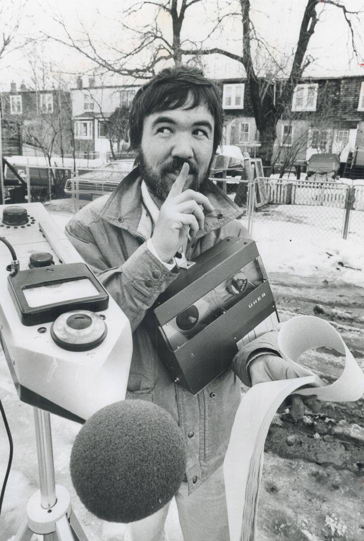 Signalling for silence, noise technician Allen Sweet takes a reading yesterday at the end of a lane east of Pickering St., in the Danforth-Kingston Rd(...)