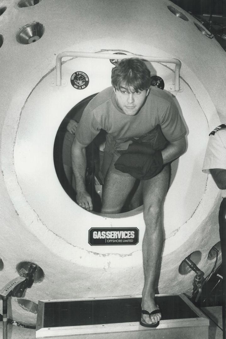 Up from the deep!, Diver John Buck, one of four Royal Navy divers who spent 28 days testing equipment in the deep, climbs out of a compression chamber at Canadian Forces Base Downsview yesterday