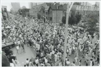 A street scene where the streets are overflowing with pedestrians on the sidewalks and the road…