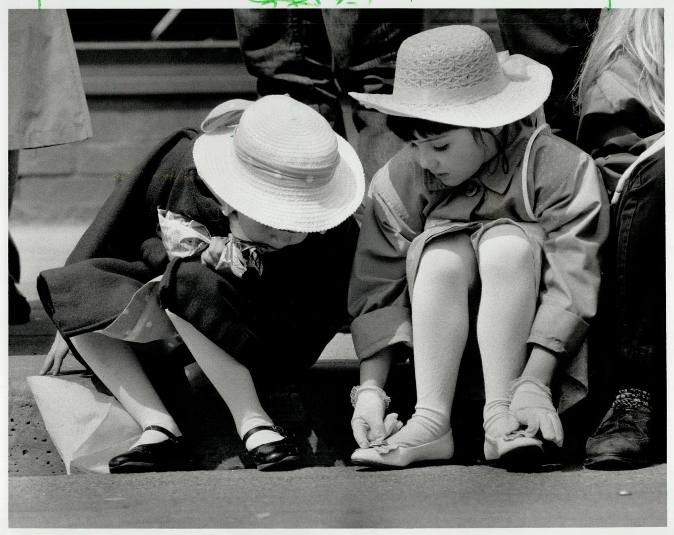 Bonnets and bows: Elizabeth Provan, 5, left, and Ashley Mullen, 5, in white stockings hats and dresses eye Sunday-best shoes from their sidewalk perch