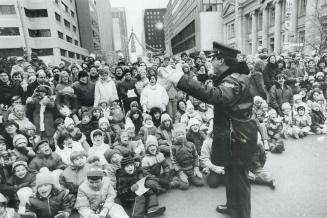 A Metro police sergeant urges a chanting, cheering crowd of kids to give a big 'hooray' for jolly old St