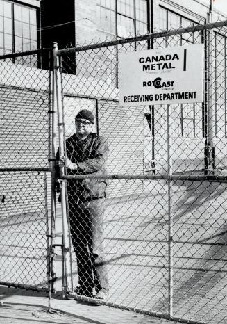 Worker stands inside wire fence of Eastern Ave