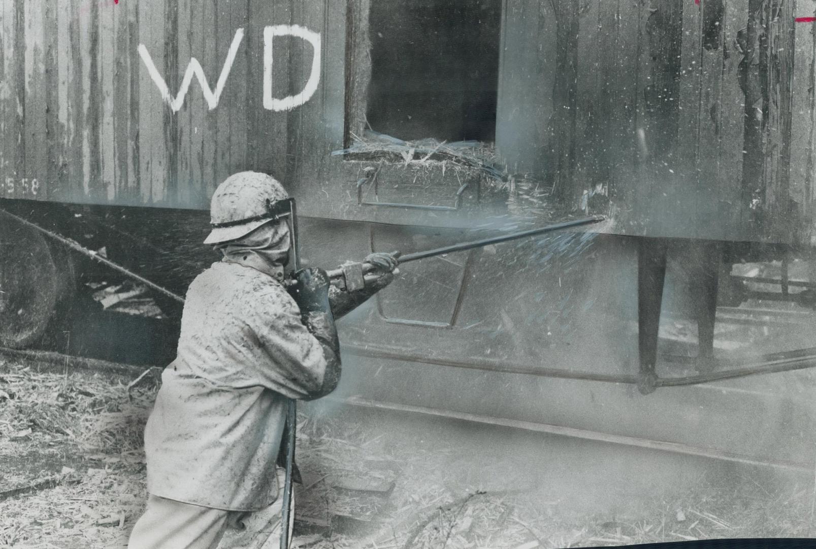 Aiming a water jet backed by 10,000 pounds of pressure, a workman starts ripping apart a railway boxcar that is to be demolished for scrap on site in (...)