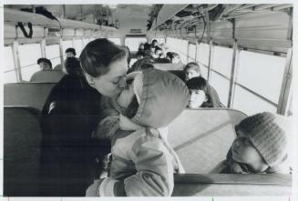 Deizira Andrade kisses her daughter Victoria, 7, goodbye as a busload of children get ready to leave the closed St