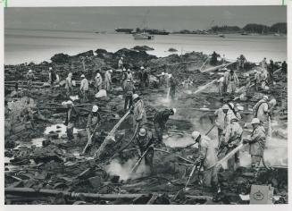 Workers attack the oil-fouled shore of Green Island last week