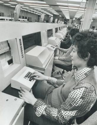 Automated sorting. Post office workers sit at consols marking mail with proper postal codes before the machine directs it on its way. The post office (...)