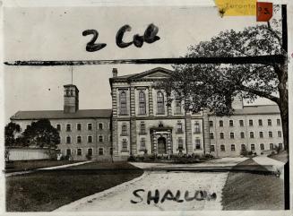 Façade of a three-storey brick building with small barred windows on either side of a protrudin…