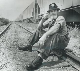 Above: Maybe he drives a Cadillac to the office - but here he's just another hobo waiting for a train