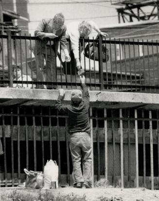 Helping handout: A passerby hands hobo king Andy Caruso a dollar bill for a treat as he stands in front of the steel fence blocking his cave under a Parkdale bridge