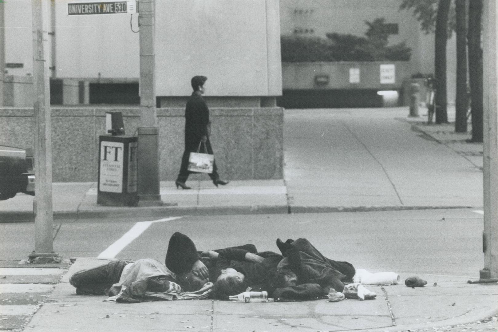 Comfort from the cold, Four people sleep huddled for warmth over a steam outlet on the median of University Ave