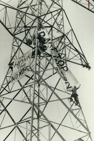 High-level protest, Three demonstrators lash banners to a 200-foot transmission tower near Bowmanville to protest construction of the Darlington nuclear plant without environment studies