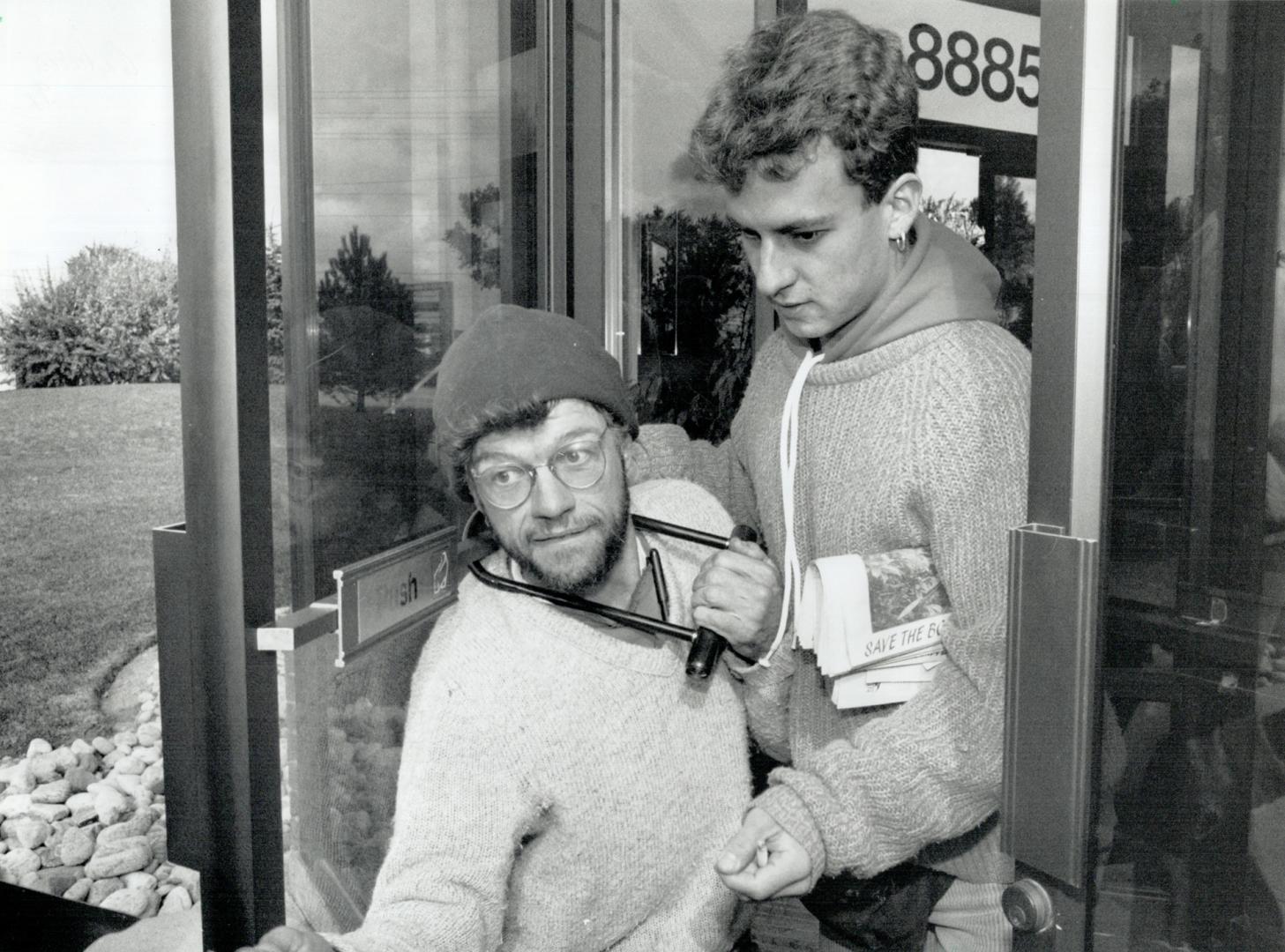 Locked in conflict, A man, left, uses a U-shaped lock around his neck to attach himself to a door at the Mitsubishi Electric offices in Markham yester(...)