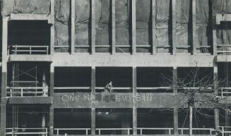 Workmen remove civil rights slogan from new court building under construction across from the United States Consulate