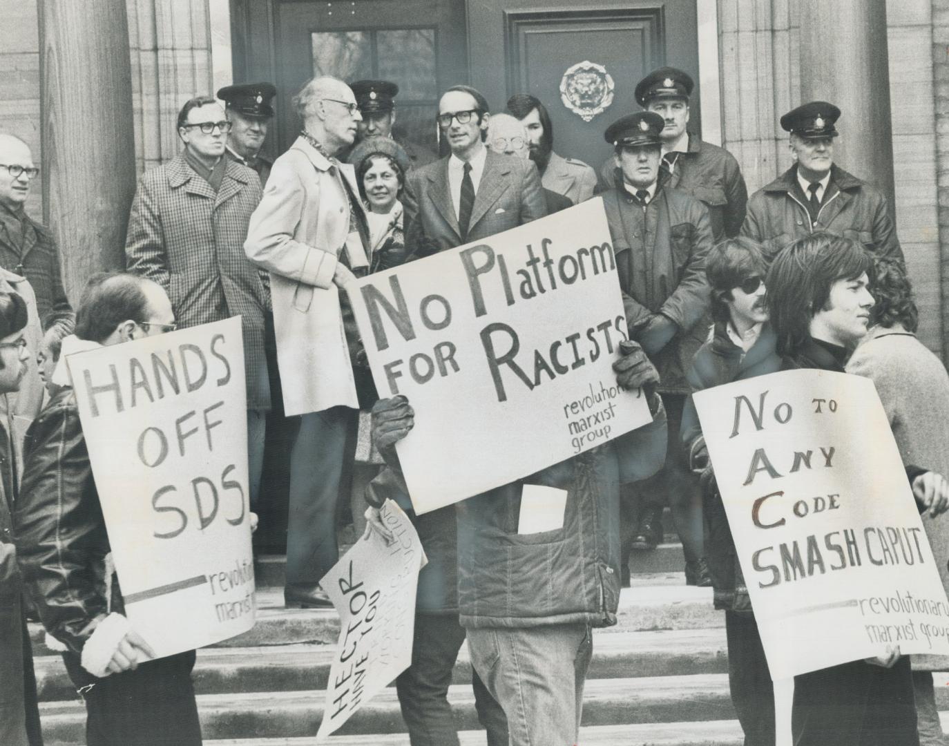 U of T president John Evans, centre, stood on the steps of Simcoe Hall last month watching demonstrators