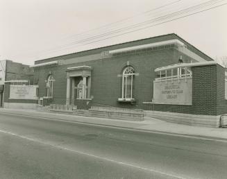 Street view of library with cement ramp at entrance. Etched signs on either side of entrance re…