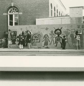 Children painting a mural on construction hoardings.