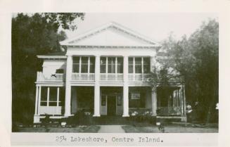 Photo of a grand two storey cottage with pillars, balcony and verandah. 