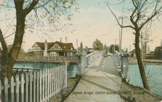 Colorized photograph of a foot bridge crossing a lagoon with a large house to the left of the p…