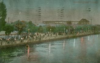 Picture shows people walking along a promenade at night. Roller coaster is in the background.