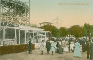 Picture shows a crowd of people outside the entrance to a roller coater ride.