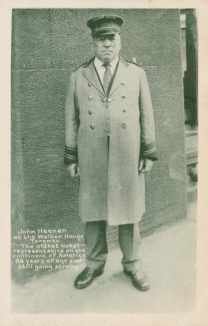 Black and white photo postcard of Doorman John Heenan, standing in front of Walker House Hotel,…