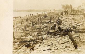 Sepia toned photograph of burnt remains of a large structure.