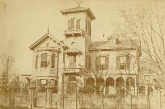 A photograph of a house with a fence in front of it.