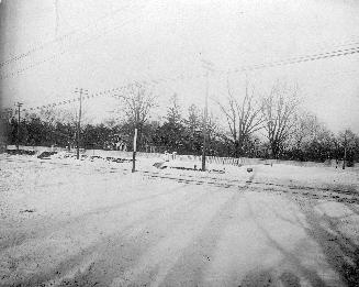 A photograph of a road and a fence in the background.