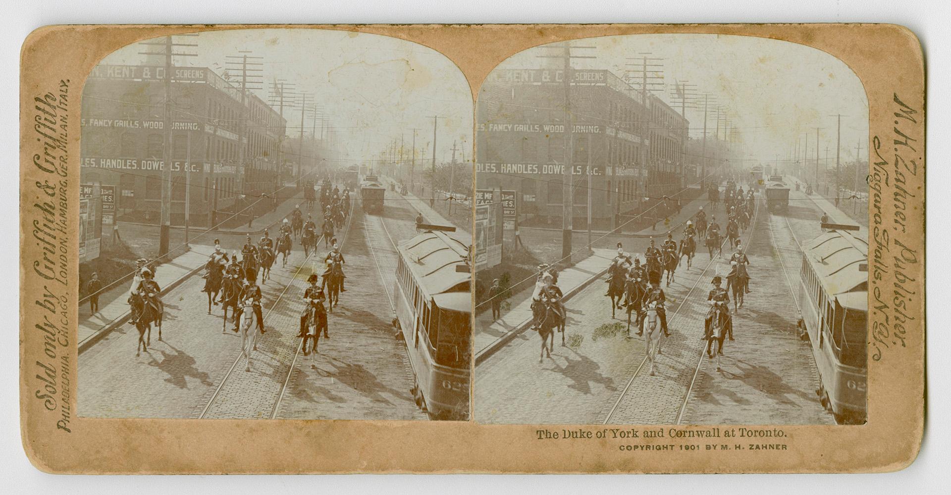 A group of men in military uniforms riding on horses in a city street.