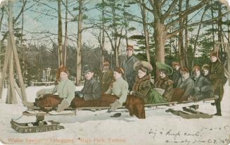 Twelve people posing on a very long toboggan.