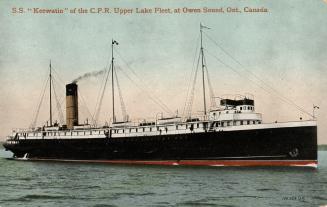 A large black steamship on a lake.