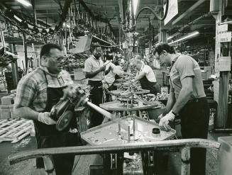 A photograph of factory workers building washing machines on an assembly line.