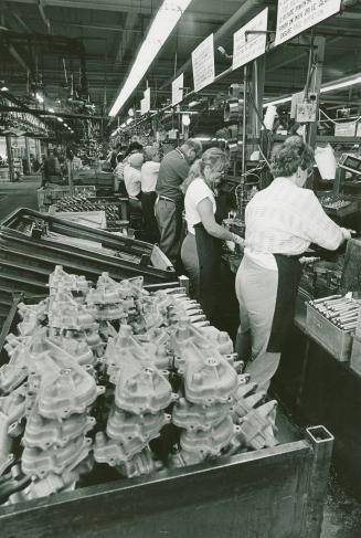 A photograph of factory workers building washing machines on an assembly line.