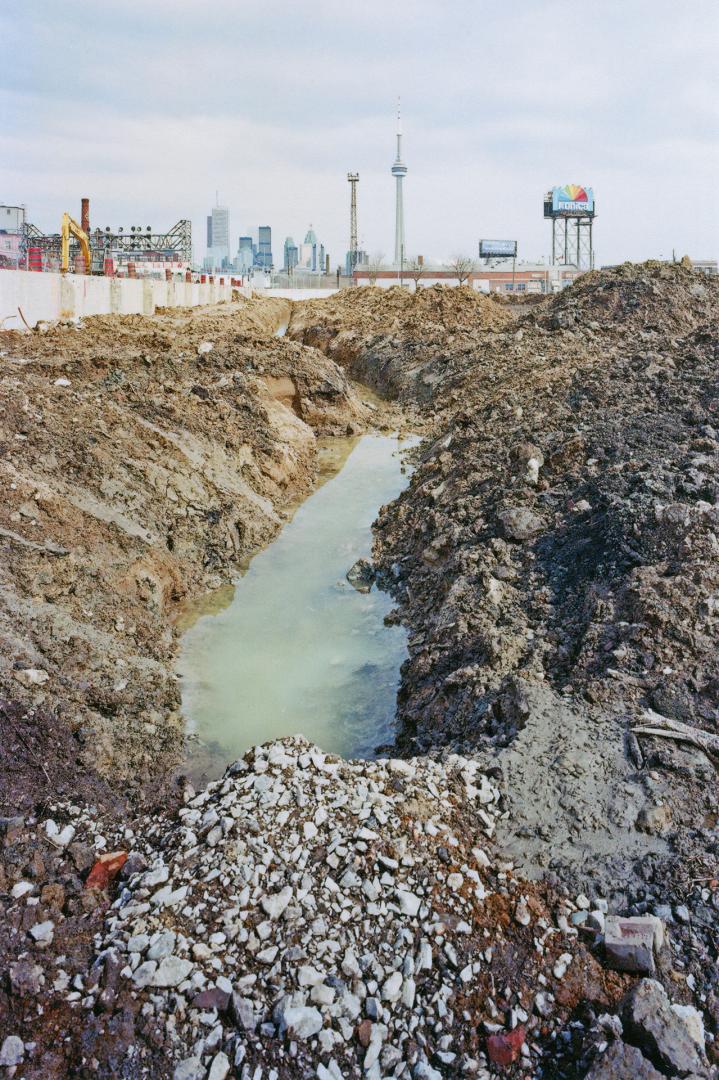 A photograph of a highway overpass, with the Toronto skyline visible in the background.