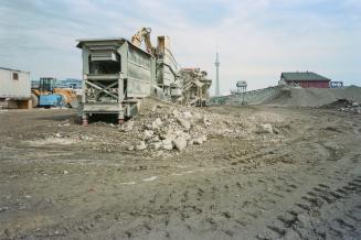 A photograph of construction equipment in the middle of a muddy field, with a shed and the CN T…