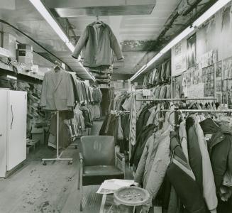 A photograph of a clothing store, with hanging racks of clothing including coats and jackets vi…