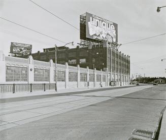 A photograph of a building on the left side of a road. Above the building is a Loblaws billboar…