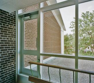 A photograph of a landing at the top of a stairwell, with a window overlooking a roof.