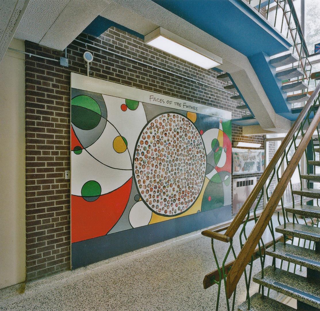 A photograph of a public school hallway, with a mural entitled &quot;Faces Of The Future&quot; …