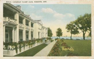 Colorize photograph of the front a a large building with a veranda. Manicures lawn; lake with b…