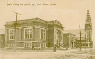 Sepia toned picture of a two story public building. Other building and a church are in the back…