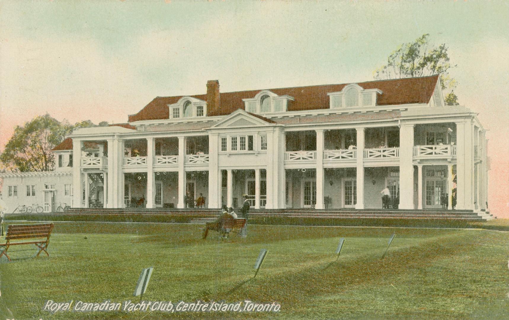 Colorized photograph of a three story, white Edwardian building with long front porches.