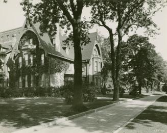 Victorian house with ivy on walls and large trees and driveway